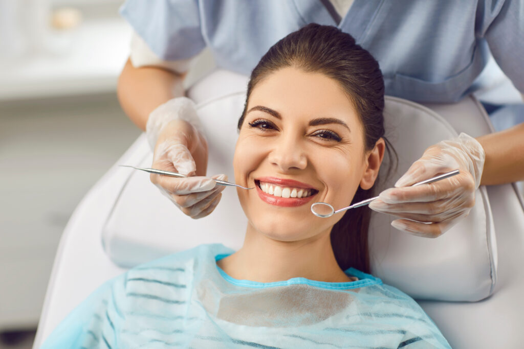 Portrait Of Smiling Patient And Dentist Checking Teeth With Instrument