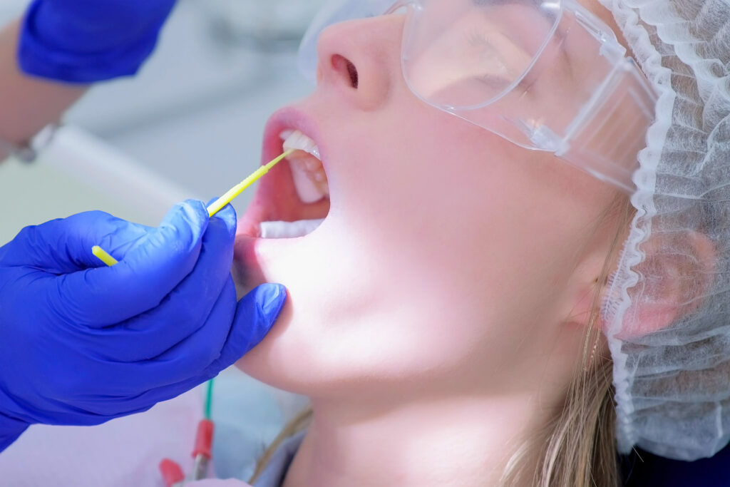 Dentist make fluoridation of teeth after ultrasonic cleaning for young woman.