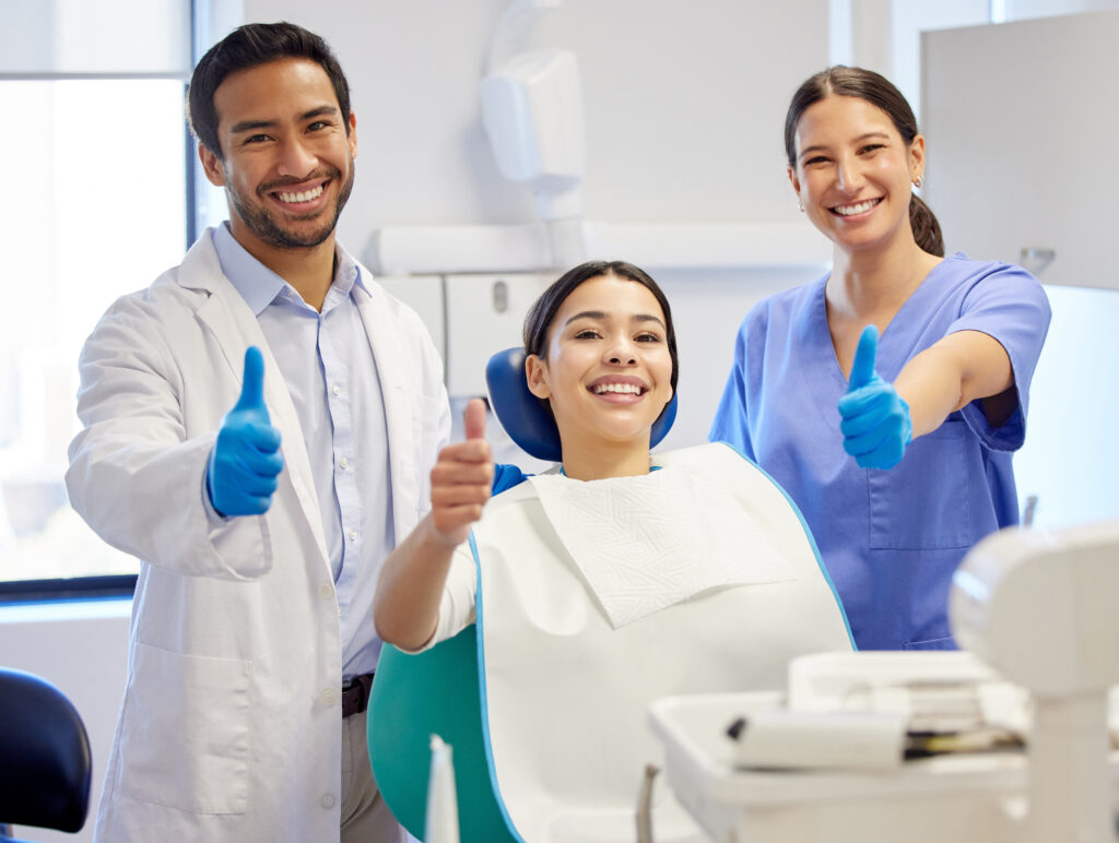 Dentist team, patient and thumbs up portrait for.consultation, clean or teeth whitening. Woman, asian man or healthcare staff and client together for dental care, oral health exam and mouth cleaning