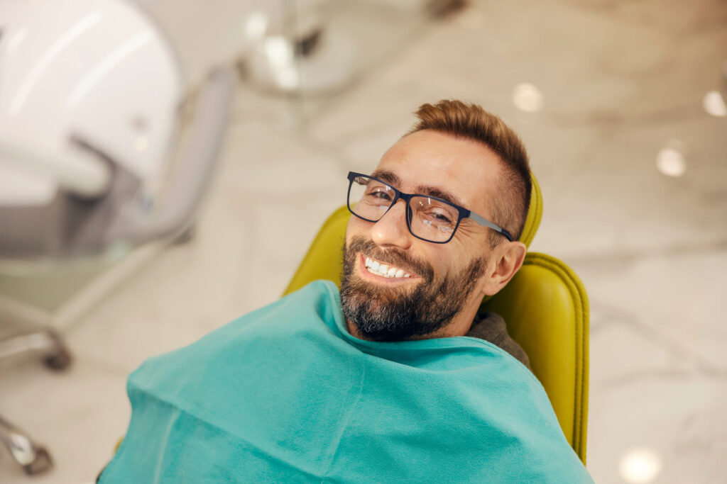 Portrait of a patient at dentist office sitting in the chair while smiling at the camera with perfect smile.