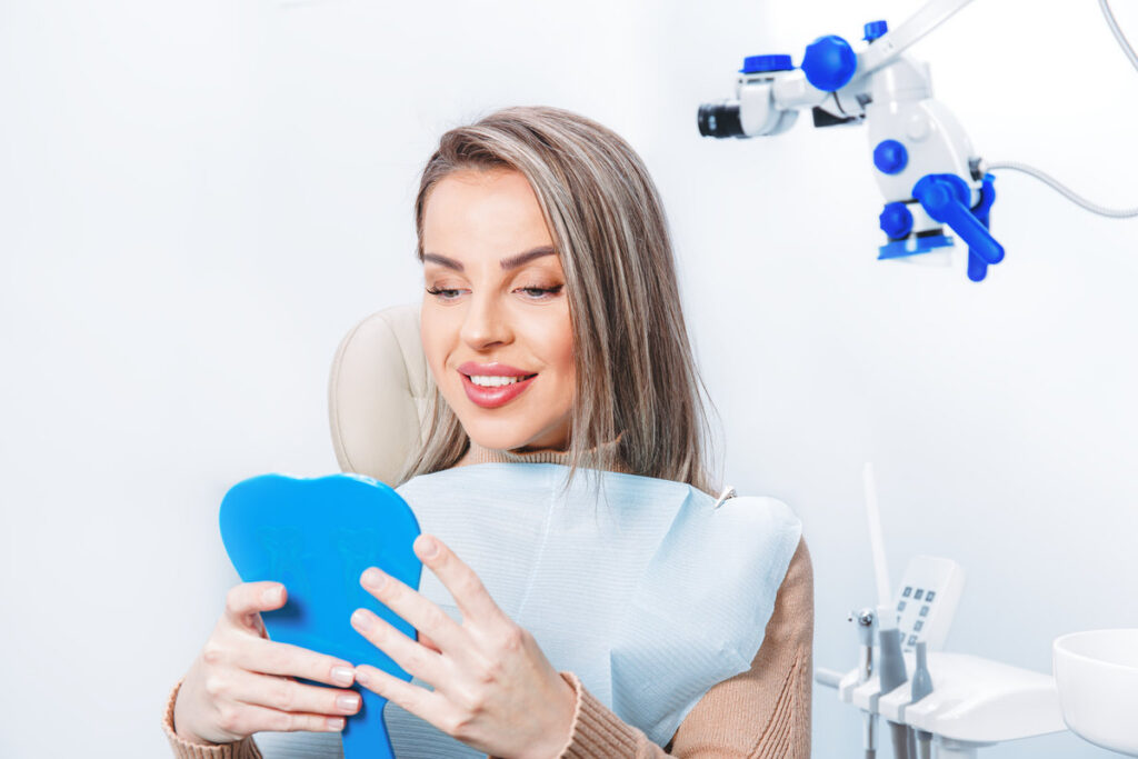 Woman looking at her teeth. Smiling lady at dentist office. Dentist treatment, perfect smile