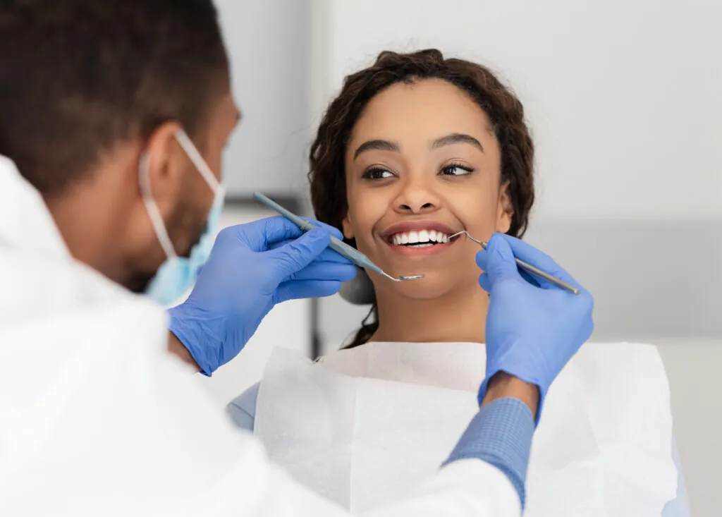 Pretty black lady looking at her dentist with smile
